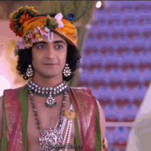 a man with a peacock feather on his head is wearing a turban and necklace .
