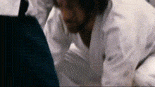 a man in a white coat is kneeling down in front of a computer screen .