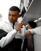 a man in a white jacket is standing next to another man on an airplane .