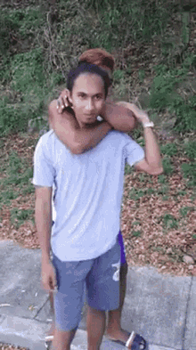 a man in a blue shirt is carrying another man on his shoulders .