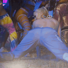 a woman in a tie dye outfit is kneeling down in the grass