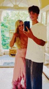 a woman in a pink dress takes a selfie with a man in a white shirt