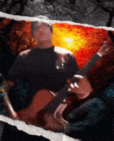 a man in a black shirt is playing a guitar in front of a sunset