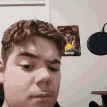 a young man stands in front of a microphone with a poster on the wall behind him that says oioatom