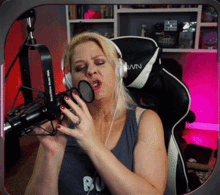 a woman wearing headphones is singing into a microphone with the word wn on the back of her chair