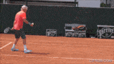 a man is playing tennis on a court with a perrier sign in the background