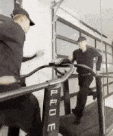 a man is running on a treadmill in front of a mirror while another man looks on .