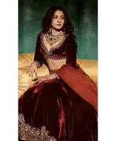 a woman in a maroon velvet dress sits on a couch