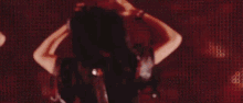 a woman is dancing in front of a red background with a lot of lights .