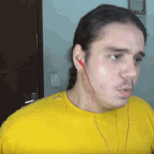 a man in a yellow shirt is wearing red ear buds
