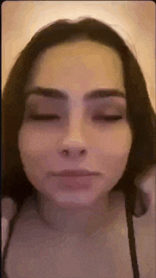 a woman with a nose ring is making a face with her eyes closed .