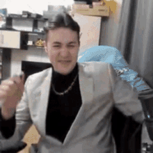 a man in a suit and turtleneck is sitting in a chair in a room .