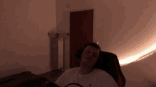 a man wearing headphones is laying in a chair in a dark room with a banana on the wall behind him