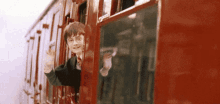 harry potter is waving out of a train window .