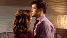 a man in a plaid shirt kisses a woman on the forehead