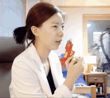 a woman in a white coat is holding a red toy gun