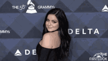 a woman stands on a blue carpet with delta and emmys logos
