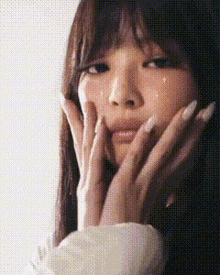 a close up of a woman 's face with her hands on it .