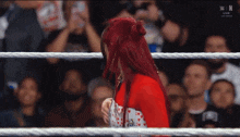 a woman with red hair stands in a wrestling ring