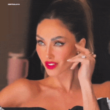 a woman with red lipstick and a ring on her finger is looking at the camera