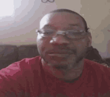 the man is wearing glasses and a red shirt .