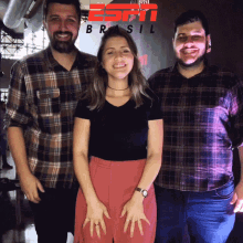 three people posing for a picture in front of a sign that says brasil