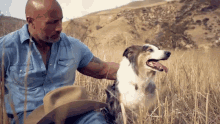 a bald man in a cowboy hat is petting a dog