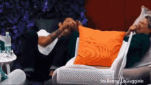a man and a woman are sitting on a couch with a pillow that says ste benny leguggiole