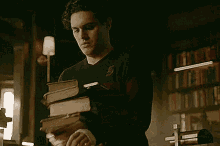 a man is standing next to a stack of books in a room .