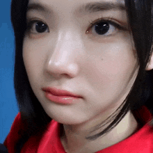 a close up of a person 's face with a red shirt on