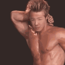 a shirtless man with his hand on his head looks at the camera