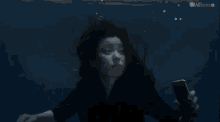 a woman is underwater holding a bottle with the allseries logo on the bottom