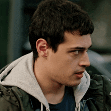 a young man wearing a grey hoodie and a black shirt