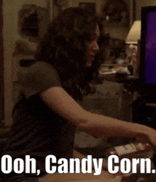 a woman sitting in front of a television with the words ooh candy corn written below her