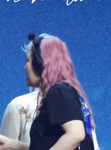 a woman with pink hair wearing headphones and a black shirt