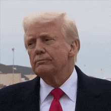 a close up of donald trump 's face in a suit and red tie