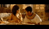 a man and a woman are sitting next to each other in a room and talking to each other .