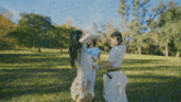 three women are standing in a field holding hands