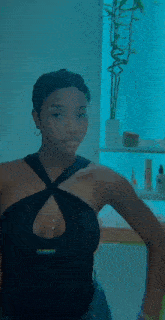 a woman in a black dress is standing in front of a mirror .