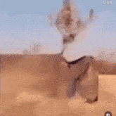 a person is standing in the middle of a desert holding a gun .