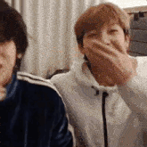 a man is covering his mouth with his hand while laughing .