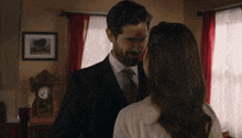 a man in a suit and tie is looking at a woman in a white shirt