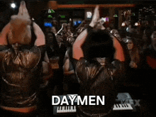 a man is playing a keyboard in front of a crowd and the word daymen is on the bottom