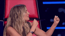a woman is sitting in a red chair with her fist up