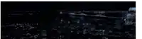 a blue car is driving down a road at night .