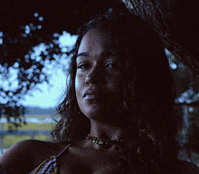 a woman in a bikini is standing under a tree in the dark