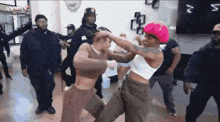 a woman in a pink hat is fighting another woman