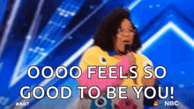 a woman singing into a microphone with the words `` oooo feels so good to be you ''