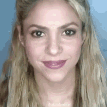 a close up of a woman 's face with long blonde hair and a purple lip .