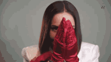 a woman wearing a white jacket and red gloves covering her face